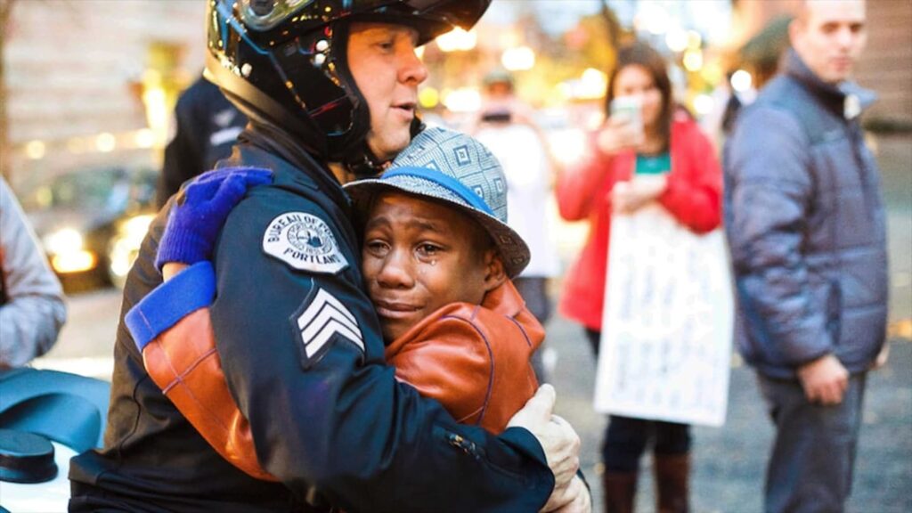 Devonte Hart hugs Portland police Sergeant Bret Barnum at a rally in Portland in 2014.(AP: Johnny Huu Nguyen)